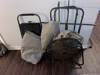 Full lot showing black metal fan, folded gray air mattress bag, gray step stool, and parts of black laundry basket frame with attached fabric parts.