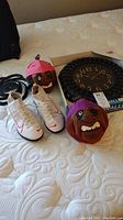 Nike white shoes, two Bahamian coconut decors with cartoon faces and hats, and Westminster clock placed on bed