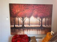 Canvas painting on wall featuring red-leafed trees by water with reflection, scratches visible