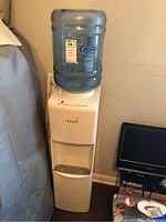 Full view of Primo white electric water cooler with blue 5-gallon water bottle on top