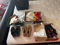 Photo of all five pairs of shoes on a bed, some in and some out of boxes