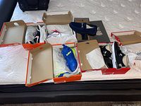 Photo showing six pairs of shoes with boxes including Nike and Stacy Adams on bed