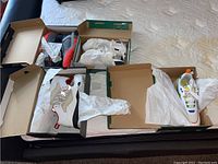 Top view of 4 pairs of shoes in boxes on bed showing shoe colors and styles.