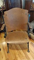 Front view of the antique theater seat showing wooden seat and backrest with cast iron armrests and frame.