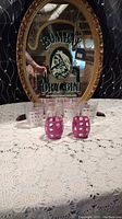 Vintage Bombay Dry Gin advertising mirror with ornate gold frame, featuring an image of a woman and lettering, with 2 pink polka dot glasses in front.