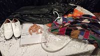 Full costume laid out on a white lace tablecloth with visible orange pants, multicolored shirt, jacket, white shoes and accessories.