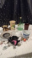 Photo showing mixed lot including glass, ceramic, and metal bowls, vases, and decorative items on lace tablecloth