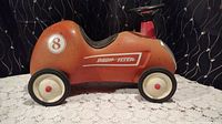 Side view of rust-colored Radio Flyer push car Model 8 with white wheels and number 8 decal on side.