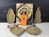 Photo showing King Arthur Flour Cookie Companion cookbook and four vintage metal cookie molds for Halloween, Christmas, Valentine’s Day, and a holiday wreath design.