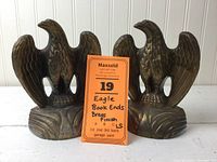 Pair of brass finish eagle bookends shown side by side with informational tag