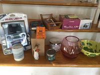 Shows all items placed on wooden surface including label maker in package, camera box, Willow Tree figurine, candles, decorative bowls, and wooden tray.