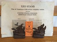 Pair of carved wooden duck bookends in front of folder with collection title and description sticker