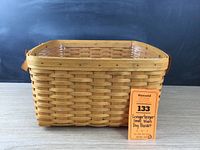 Front view of small Longaberger basket with plastic liner inside and leather handles visible at top edge.