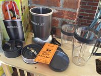 Photo showing blender base, two clear cups, lids, blade assembly, sealing rings, user manual, and box.