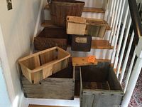 Full view of vintage wooden boxes and apple baskets arranged on stairs showing various sizes and types including flat rectangular boxes and larger square boxes plus wooden apple baskets.