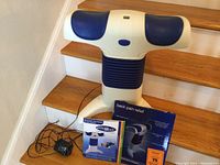 Photo shows the Back2Life Personal Back Therapist device on wood stairs, with power adapter attached.