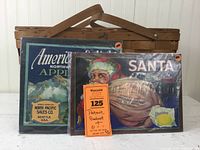 Photo showing Basketville picnic basket with two vintage fruit crate labels leaning against it. Labels are colorful and depict apples and oranges.