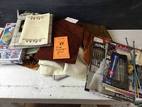 Full overview of wool fabrics, tools, and instruction materials on white surface