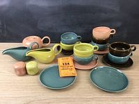 Full view of the 21 piece vintage Russel Wright china set showing cups, saucers, teapot, creamers, salt and pepper shakers, and plates in pastel colors.