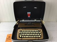Full view of tan/brown Smith-Corona Galaxie Twelve typewriter inside its black carrying case, showing keyboard and case interior.
