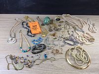 Full overview of the lot laid out showing necklaces, bracelets, earrings, and green decorative egg