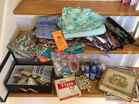 Wide view showing multiple fabric pieces, fabric binding, buttons, and other sewing supplies on display