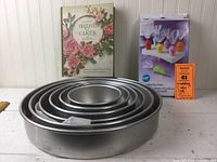 Side view of stacked round cake pans with the book and decorating bag holder behind them.