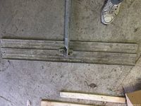 4 ft magnesium bull float with a flat head and metal handle laid on concrete floor, showing signs of use.