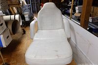 White massage chair with padded armrests and visible cracking on center seating upholstery, showing stains and wear.