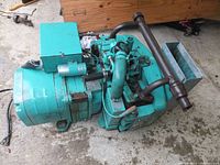 Overall top‐down view of teal generator showing engine, alternator housing, exhaust manifold and control box