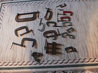 Overall view of 2 vintage vises and 17 vintage C clamps arranged on a carpet.