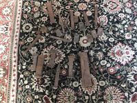 Top-down photo of all wooden wedges and metal chisels arranged on patterned carpet, showing size variation and use wear