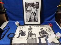 Velvet Underground black and white poster with three band members and instruments, 27 x 19 inches, displayed flat with some other objects.