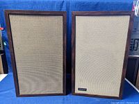 Front view of the pair of Advent Model 1 speakers with cloth grilles in place, wood cabinets visible.