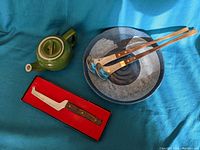 Full lot showing green tea pot, pottery dish, two utensils, and cheese tool in box