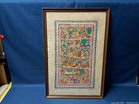 Photo of the framed Middle Eastern papyrus painting showing the full artwork with vibrant colors and detailed, traditional scenes.