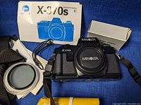 Minolta X-370s camera body with instruction manual, color filter kit box, and various accessories.