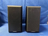 Pair of Mission bookshelf speakers with black mesh covers, front view.