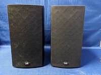 Front view of the pair of PSB Image B15 bookshelf speakers with black cloth grilles and PSB logos visible, showing some wear.
