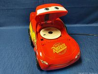 Red sports car shaped novelty radio/CD player with Rust-eze logo and number 95 decals. Hood opened showing a CD inside the player.