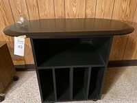Front view of the black TV stand showing open shelves and vertical dividers
