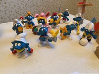 Smurfs figurines showing various characters and poses on white surface.