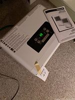 Top angled view of Honeywell dehumidifier showing digital control panel set at 30, with instruction manual beside it.