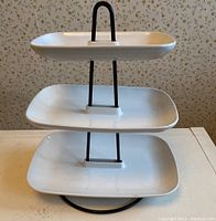 3-tier serving tray with three white rectangular plates and black metal frame