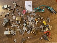 Top-down view of assorted old keys spread on a wooden surface showing quantity and variety