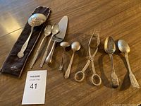 Photo showing entire lot of eight serving utensils on wood surface with MaxSold tag 41