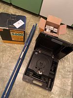 Kodak Carousel 5600 slide projector open showing rotary slide tray area with carrying case and tripod stand parts nearby.