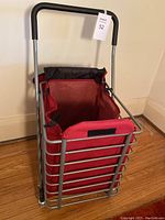 Folding shopping cart upright showing red fabric liner and soft rubber handle