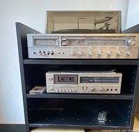 Full view of Viking stereo receiver on top shelf, cassette deck on middle shelf inside black shelf unit with pull-out shelf partially visible