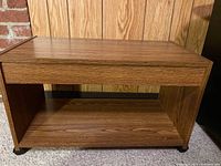Photo of wooden TV stand showing its rectangular top surface and open shelf below.